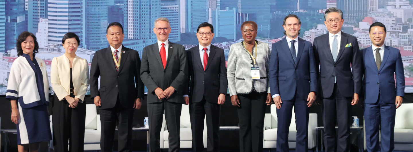 Nine people in business attire stand on a stage in front of a city skyline backdrop.